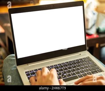Home office work. Empty blank screen, male hand typing on a laptop computer keyboard, open notebook on legs, copy space, template Stock Photo