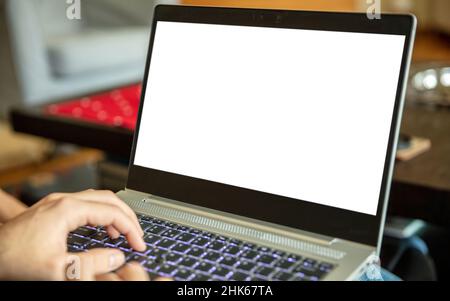 Home office work. Empty blank screen, male hand typing on a laptop computer keyboard, open notebook on legs, copy space, template Stock Photo