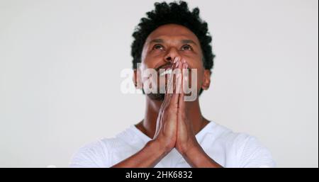 Black African man praying looking up to the sky with hope and faith Stock Photo