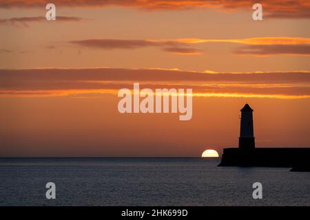 Sunrise behind the light tower at the entrance of Berwick upon tweed harbour Stock Photo