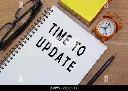 Time to update text on notepad with alarm clock on wooden desk. Time management concept Stock Photo