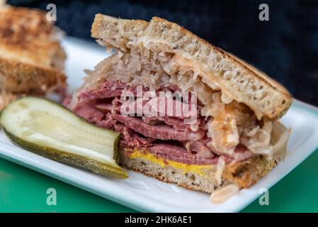 Closeup of Reuben Sandwhich with Corned Beef, Sauerkraut, Mustard and Pickle Stock Photo