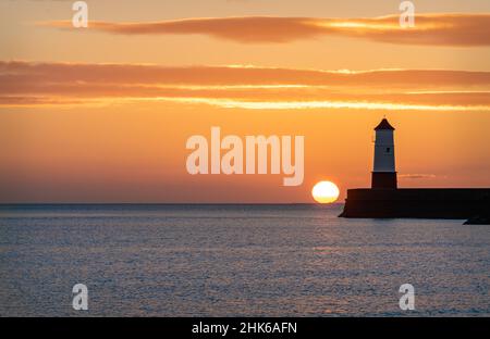 Sunrise behind the light tower at the entrance of Berwick upon tweed harbour Stock Photo