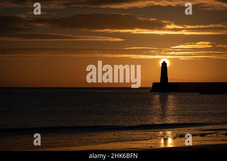 Sunrise behind the light tower at the entrance of Berwick upon tweed harbour Stock Photo