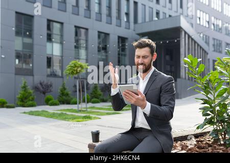 Successful salesman entrepreneur rejoices at a successful deal, receives confirmation of sale online, rejoices sitting near the office holding a table Stock Photo