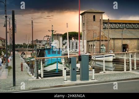 Beautiful sunset that illuminates the boats on the colorful port channel of Cervia Stock Photo
