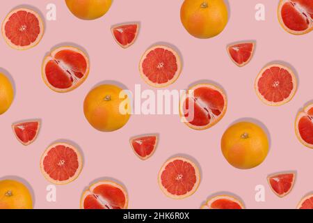 Creative pattern with fresh whole and sliced grapefruit on bright pink background. Minimal fruit concept. Vitamins, healthy diet concept.  Flat lay. Stock Photo