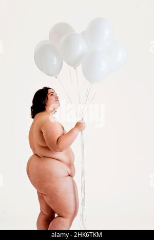 Overweight nude woman holding up white balloons Stock Photo - Alamy