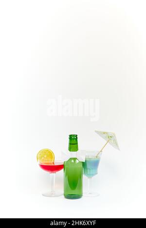 Set of empty green glass beer bottle with two equally empty transparent glass goblets on white background. Copyspace. Vertical photography. Stock Photo