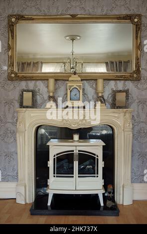 Original decorative Georgian fireplace with antique gold mirror in the living room. Stock Photo