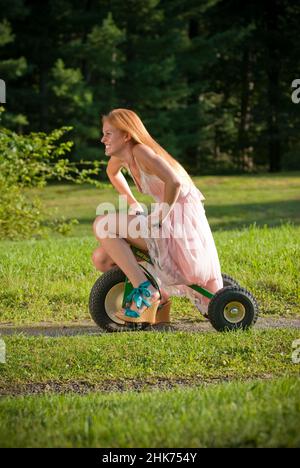 Young redheaded woman riding a child's tricycle Stock Photo