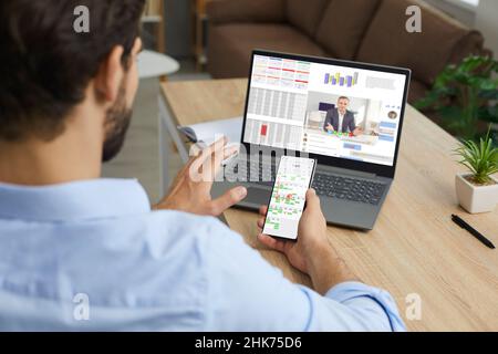 Man working at home, using laptop and phone, planning business schedule and talking via video call Stock Photo