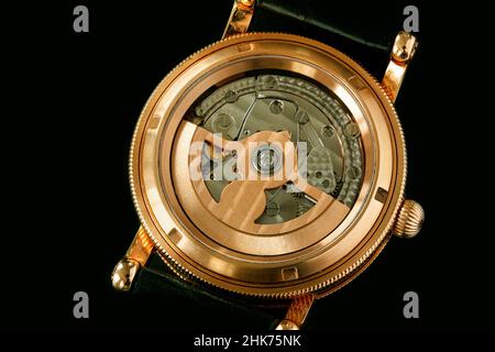 Back of luxury Swiss fashion wrist watch interior mechanism with gears and cogs. Watch With Golden Gearwheels Gears. Vintage movement mechanics. Close Stock Photo