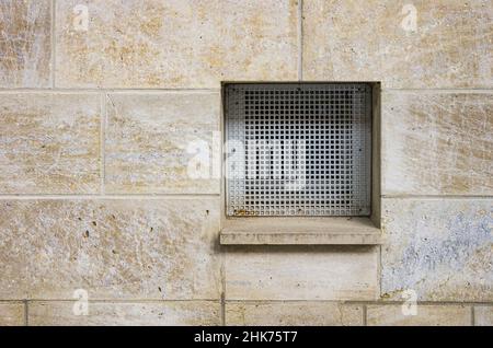 A ventilation shaft with a grille in a wall. Stock Photo