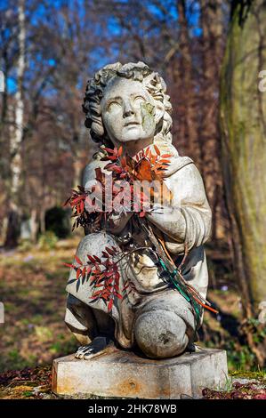 Suedfriedhof, damaged childlike figure with bundle of leaves on gravestone, Munich, Bavaria, Germany Stock Photo
