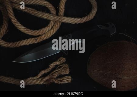 Tactical folding knife for survival, active lifestyle and recreation, on rope background and dark background Stock Photo