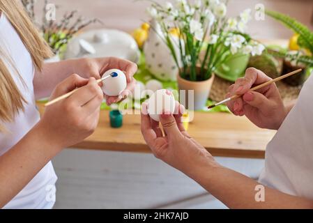 Hands of mother and daughter coloring Easter eggs. Stock Photo