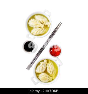 Dumplings are served in white cups with sauces on a serving board . Top view. isolated on white Stock Photo