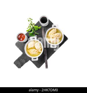 Dumplings are served in white cups with sauces on a serving board . Top view. isolated on white Stock Photo