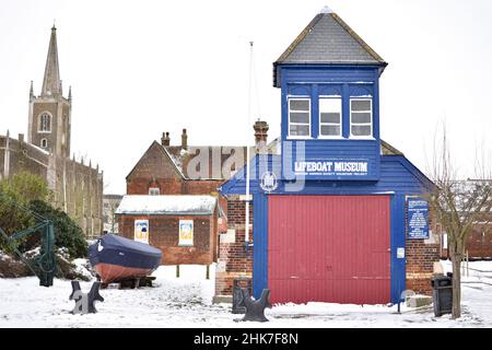 The Harwich Lifeboat house built in 1876 now a museum. St Nicholas church stands behind on a snowy day after a winter storm. Harwich, North Essex, UK Stock Photo