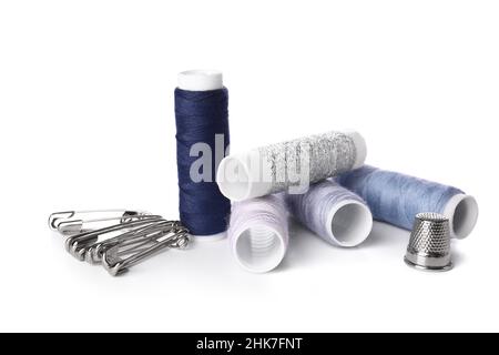 Different thread spools, safety pins and thimble on white background Stock Photo