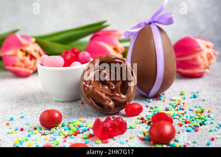 Easter eggs with chocolate paste and different candies on light background, closeup Stock Photo