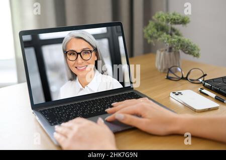 Video call to female employee or friend. Two woman is talking online via video connection on laptop indoor, they are greeting each other. Virtual meeting Stock Photo