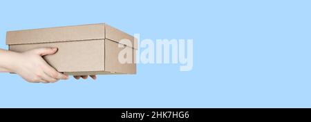 Large cardboard box in hands on blue background Stock Photo