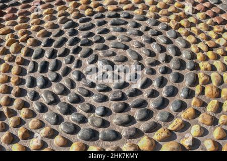 Mosaic circle pattern from convex rounded pebble stones. Ground path textured surface from boulders.Reflexology stones  Stock Photo