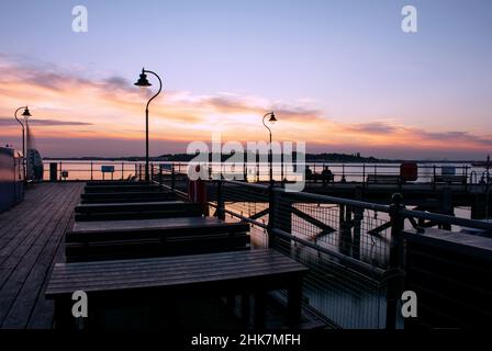 Sunset over the historic Ha'penny pier in Harwich, North Essex, UK.  The evening sky is reflected on the smooth water of the River Stour. Stock Photo