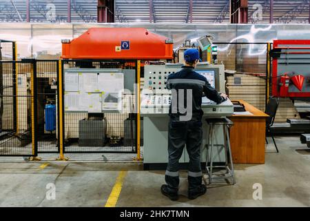 Factory worker operating CNC machine in metalworking workshop. Stock Photo