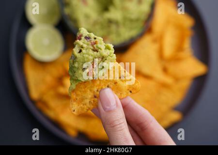 Closeup of woman hand holding guacamole and chips or nachos. Top view Stock Photo