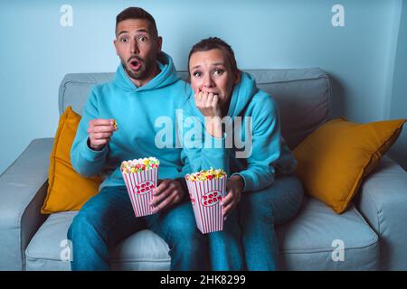Young couple with popcorn watching horror or scary movie at home Stock Photo
