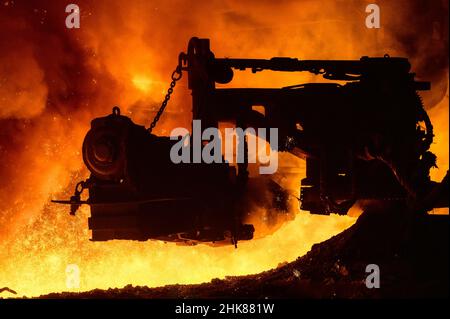 The process of releasing pig iron from a blast furnace. A man works with molten metal Stock Photo