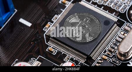 Silver Bitcoin over computer mother board, top view. Crypto money production technology and DeFi Finance system on dark CPU circuit background Stock Photo