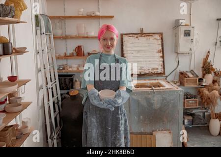 Young ceramist working with clay crockery in workroom Stock Photo