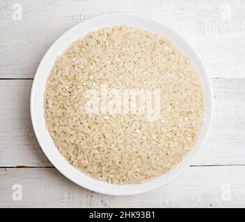 Top view of uncooked rice in glass bowl on wooden background Stock Photo