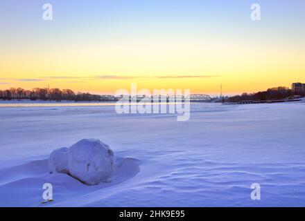 Morning on the banks of the Ob. A winter snow-covered bank of a large river, a railway bridge on the horizon. Novosibirsk, Siberia, Russia, 2022 Stock Photo