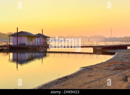 The bank of the Ob River. Sandy beach, boat pier, railway bridge on the horizon in the morning. Novosibirsk, Siberia, Russia, 2021 Stock Photo