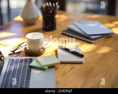 An office supplies on wooden table, Laptop computer, sticky notes, notebook, stationery, glasses and coffee cup. close-up Stock Photo