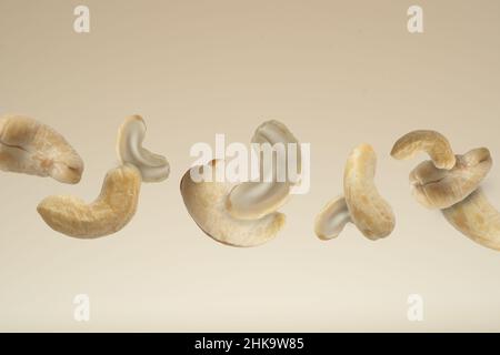 Close up photo of floating raw organic cashews on beige background. Stock Photo