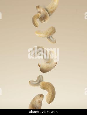 Close up photo of floating raw organic cashews on beige background. Stock Photo