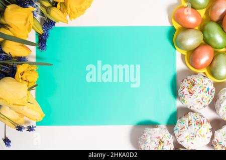 Easter layout with tulips, cakes and eggs in the form of a frame with a place for text in the center, top view. Stock Photo