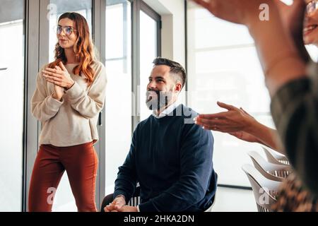 Successful businesspeople applauding in a modern office. Group of multicultural businesspeople clapping happily during a meeting. Cheerful entrepreneu Stock Photo