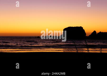 The sun setting behind sea rocks at Cape Foulwind, New Zealand. 2019 Stock Photo