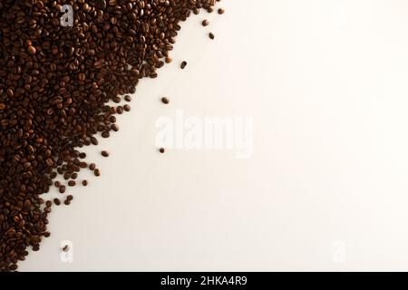 Pile of naturally dried coffee beans on one side on white table. Top view. Horizontal composition. Stock Photo