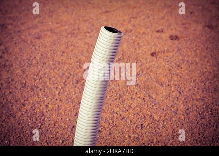 Flexible plastic pipe with electric cable coming out from the ground - toned image Stock Photo
