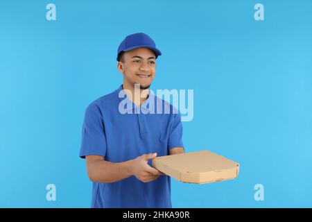 Young delivery man with pizza box on blue background Stock Photo