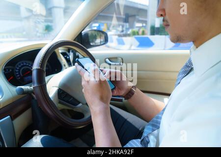 Driving car and using phone. Distracted driver texting with mobile cellphone. Irresponsible man checking message with smartphone in traffic. Auto acci Stock Photo
