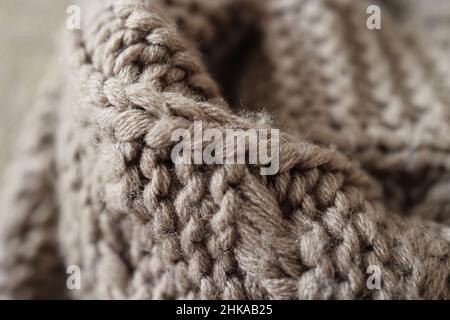Knitted large handmade plaid made of acrylic thread, very thick yarn, fashion concept. Close-up of a knitted blanket, background, selective focus. Stock Photo